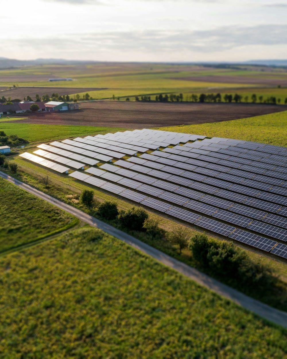 Aerial view of a ground-mounted solar farm in green fields, ECO-SFI logo