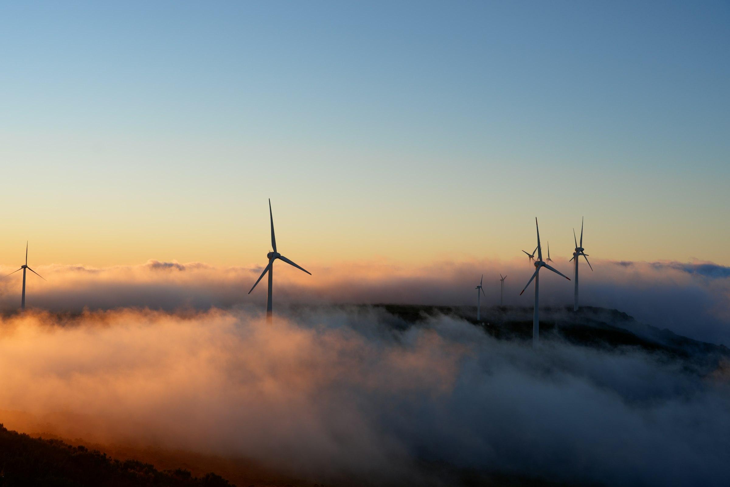 Wind turbines rising above low clouds at sunset, Portugal